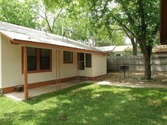 a small house with a tree in the back yard and grass on the lawn area