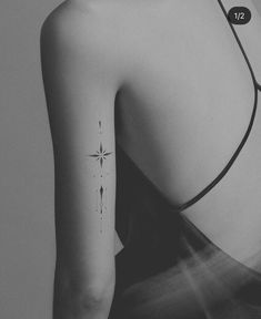 the back of a woman's shoulder with a small star tattoo on her left arm