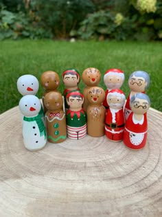 a group of wooden dolls sitting on top of a tree stump in front of some grass