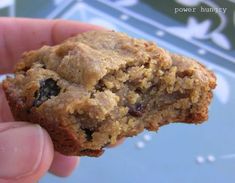 a hand holding a cookie in it's palm, with the top half partially eaten