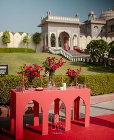 a red table with flowers and candles on it