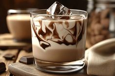 a glass filled with liquid and chocolate on top of a wooden table