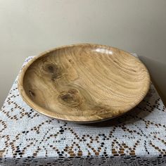 a wooden bowl sitting on top of a table next to a white doidled cloth