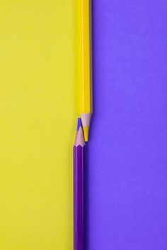 a yellow and purple pencil laying on top of each other next to an eraser