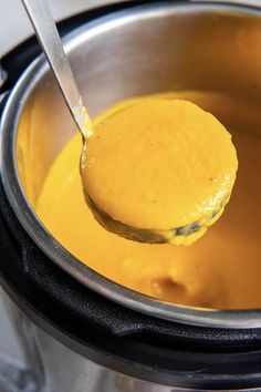 a ladle full of yellow liquid being stirred by a spoon