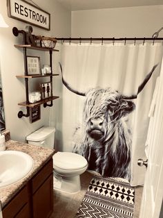 a bathroom with a cow shower curtain and rugs on the floor in front of it