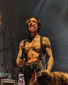 a man with tattoos on his chest holding a microphone