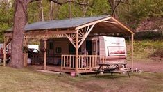 a small wooden cabin with a porch and picnic table in front of it, surrounded by trees