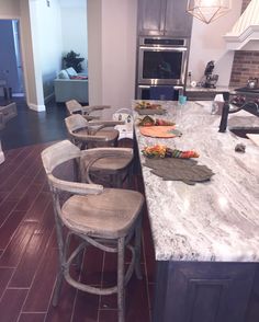 a kitchen with marble counter tops and wooden chairs