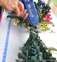 a person using a pair of scissors to cut up the stems for a flower arrangement