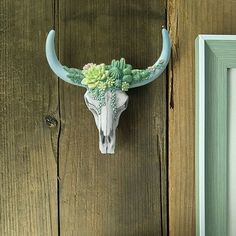 a cow's skull with flowers on it is mounted to the side of a wooden door