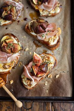 toasted bread topped with meat and vegetables on top of a baking sheet next to a wooden spatula