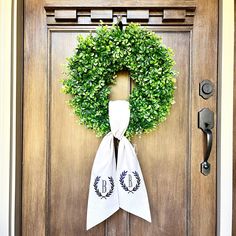 a door with a wreath and two monogrammed towels hanging from it's side