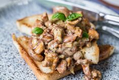 a piece of bread with meat and vegetables on it sitting on a plate next to a fork