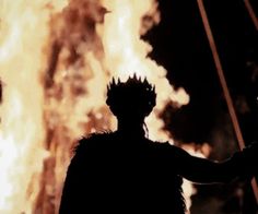 the silhouette of a man in front of a fire