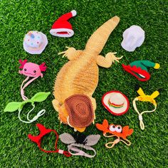 an assortment of crocheted animal toys laying on the grass with hats and other items