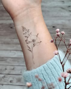 a woman's wrist with a flower tattoo on the left side of her arm