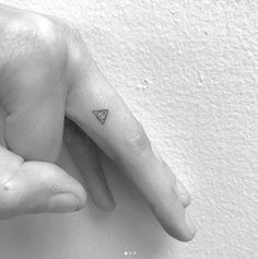 a small triangle tattoo on the left hand and right thumb, with an arrow in the middle