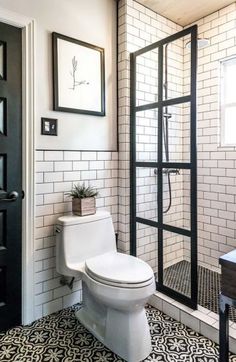 a white toilet sitting in a bathroom next to a shower and black framed pictures on the wall