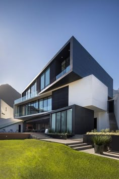 a modern house with black and white architecture on the outside, grass in front of it