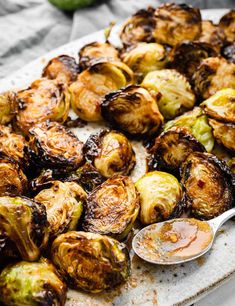 roasted brussel sprouts on a white platter with a spoon next to them