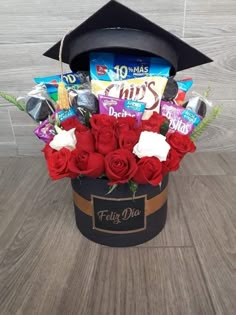 a graduation hat filled with candy and flowers on top of a wooden floor next to a wall