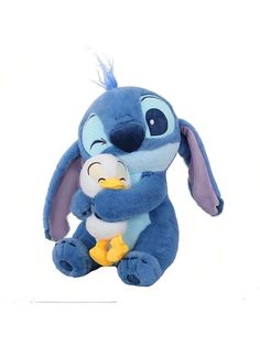 a blue stuffed animal holding a baby doll in it's arms, with its mouth open