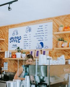 a woman standing behind a counter in a coffee shop