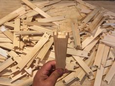 a person holding a piece of wood in front of many pieces of wooden planks