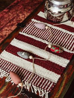 a red and white striped table runner on top of a wooden table next to a jar