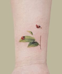 a ladybug tattoo on the ankle with leaves and two bugs sitting on it