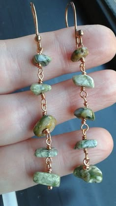 a pair of earrings with green stones hanging from them