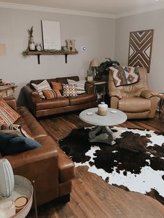 a living room with two couches and a cowhide rug on the wooden floor