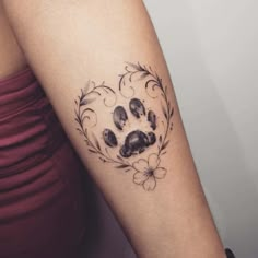 a dog paw tattoo on the left forearm and right arm, with flowers around it