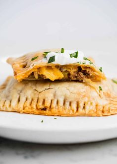 an empana filled with meat, cheese and sour cream sits on a white plate