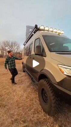 a man standing next to a van in the middle of a dry grass covered field