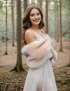 a woman in a white dress is standing in the woods with her fur stole around her shoulders