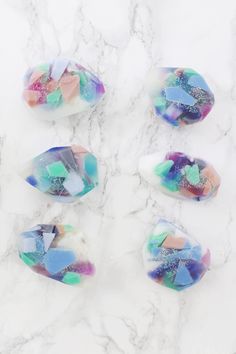 four pieces of marble sitting on top of a white counter covered in multicolored paint