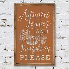 a wooden sign that says autumn leaves and pumpkins please on the side of a white brick wall