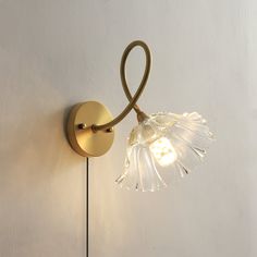 a light that is on the wall next to a white wall with a flower in it