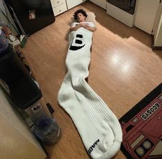 a person laying on the floor in a kitchen wearing socks with the word e printed on them