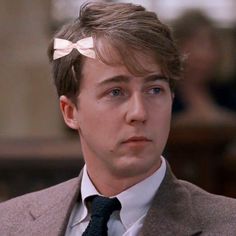 a young man wearing a suit and tie with two bows on his head looking at the camera