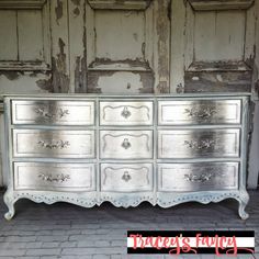 an old dresser is painted silver with white paint