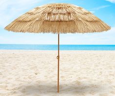 an umbrella sitting on top of a sandy beach under a blue sky and ocean in the background