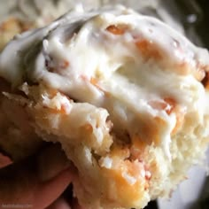 a close up of a piece of food with icing on it and someone's hand holding the pastry