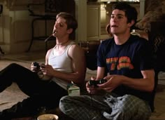 two young men sitting on the floor playing video games with remote controls in their hands