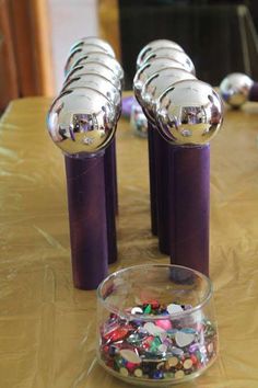 three purple vases sitting on top of a wooden table covered in confetti