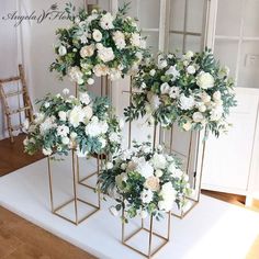 three gold vases with white flowers and greenery