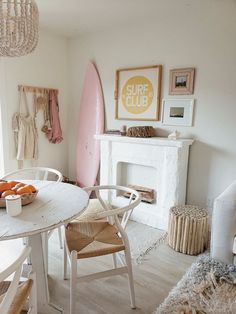 a living room with a surfboard on the wall next to a table and chairs