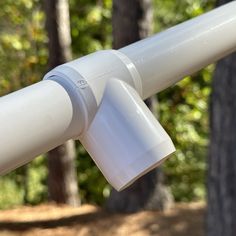 a close up view of the top of a white pipe with trees in the background